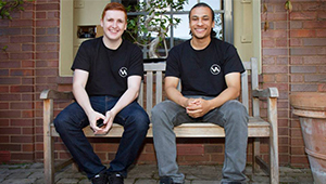 Two people in matching VOiD Applications t-shirts sitting on a bench